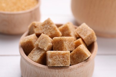 Brown sugar cubes in bowl on table, closeup