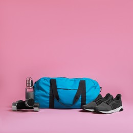 Photo of Blue gym bag and sports accessories on pink background