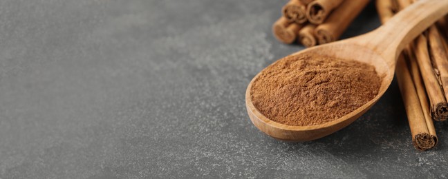 Image of Aromatic cinnamon powder and sticks on grey table, closeup view with space for text. Banner design