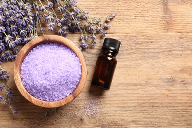 Photo of Bowl of sea salt, essential oil and lavender flowers on wooden table, flat lay. Space for text