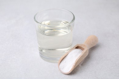 Photo of Vinegar in glass, baking soda and wooden scoop on light table