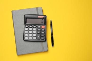 Calculator, notebook and pen on yellow background, flat lay. Space for text