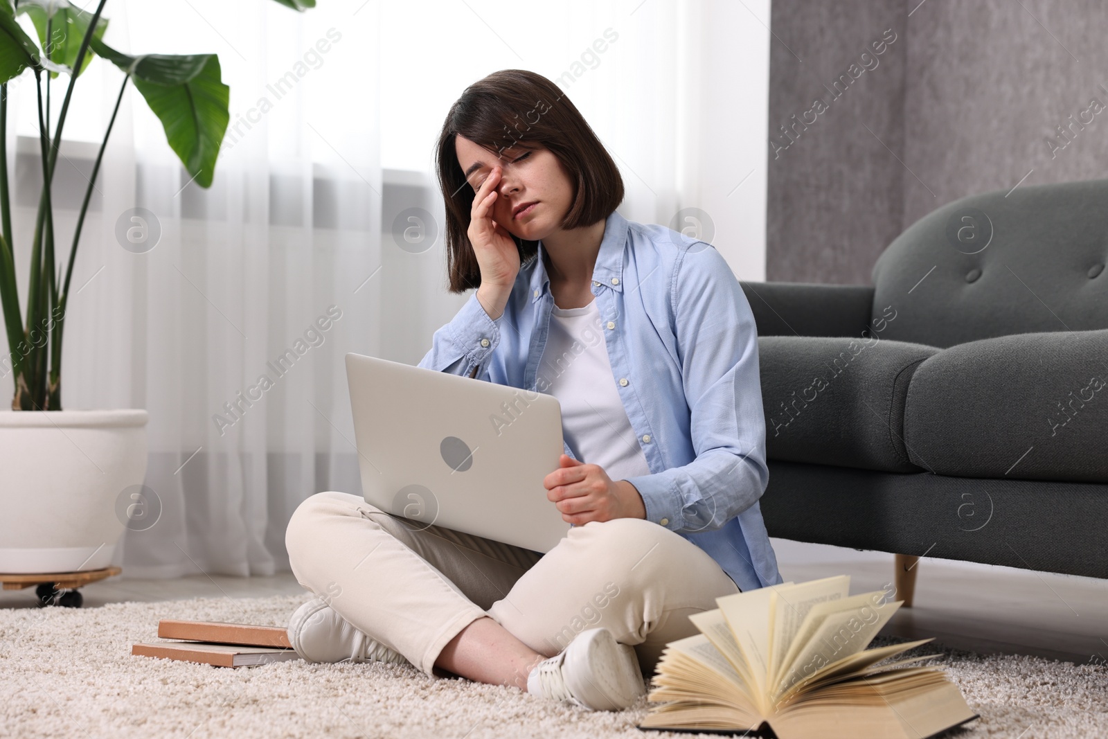 Photo of Overwhelmed woman with laptop sitting on floor indoors