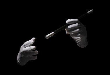 Photo of Magician with magic wand on black background, closeup