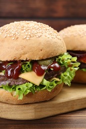 Photo of Board with delicious cheeseburgers on wooden table, closeup