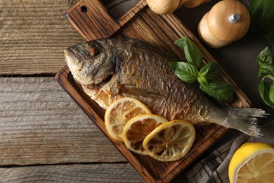 Delicious dorado fish served on wooden table, flat lay. Space for text