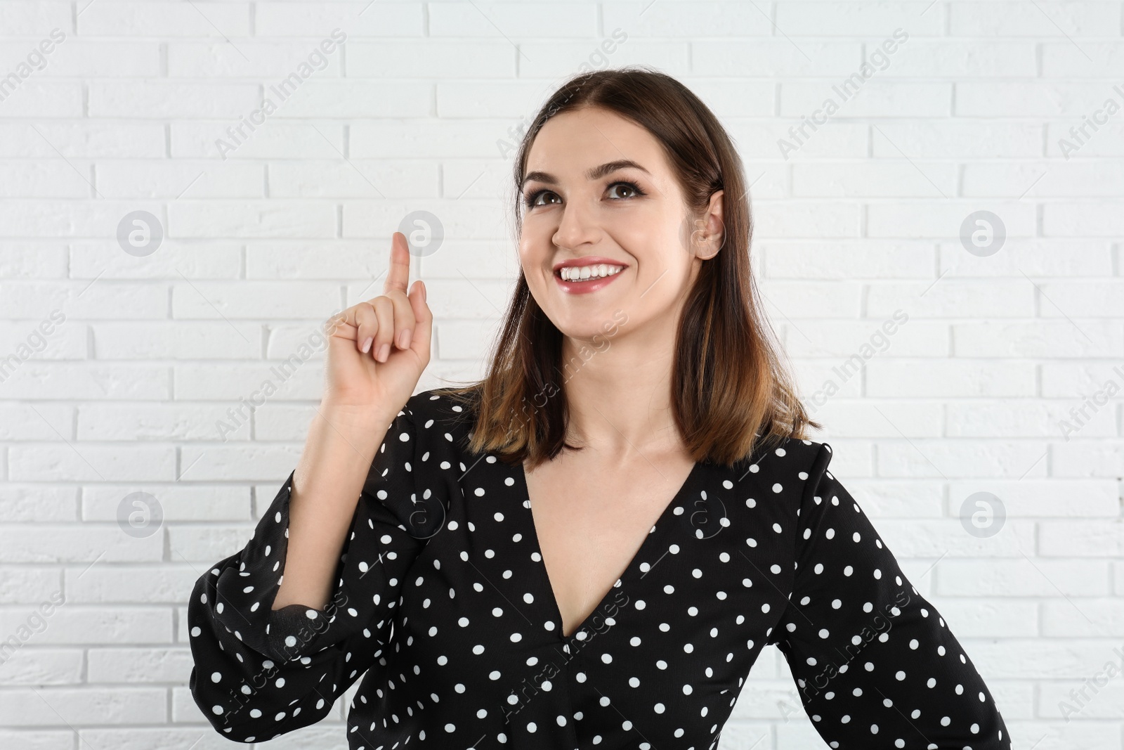 Photo of Beautiful young woman near white brick wall