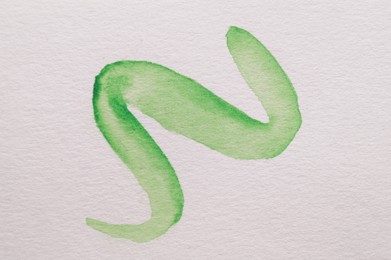 Photo of Green watercolor doodle on white canvas, top view