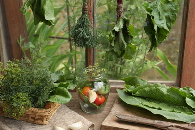 Photo of Bunches of fresh green herbs over table with ingredients indoors