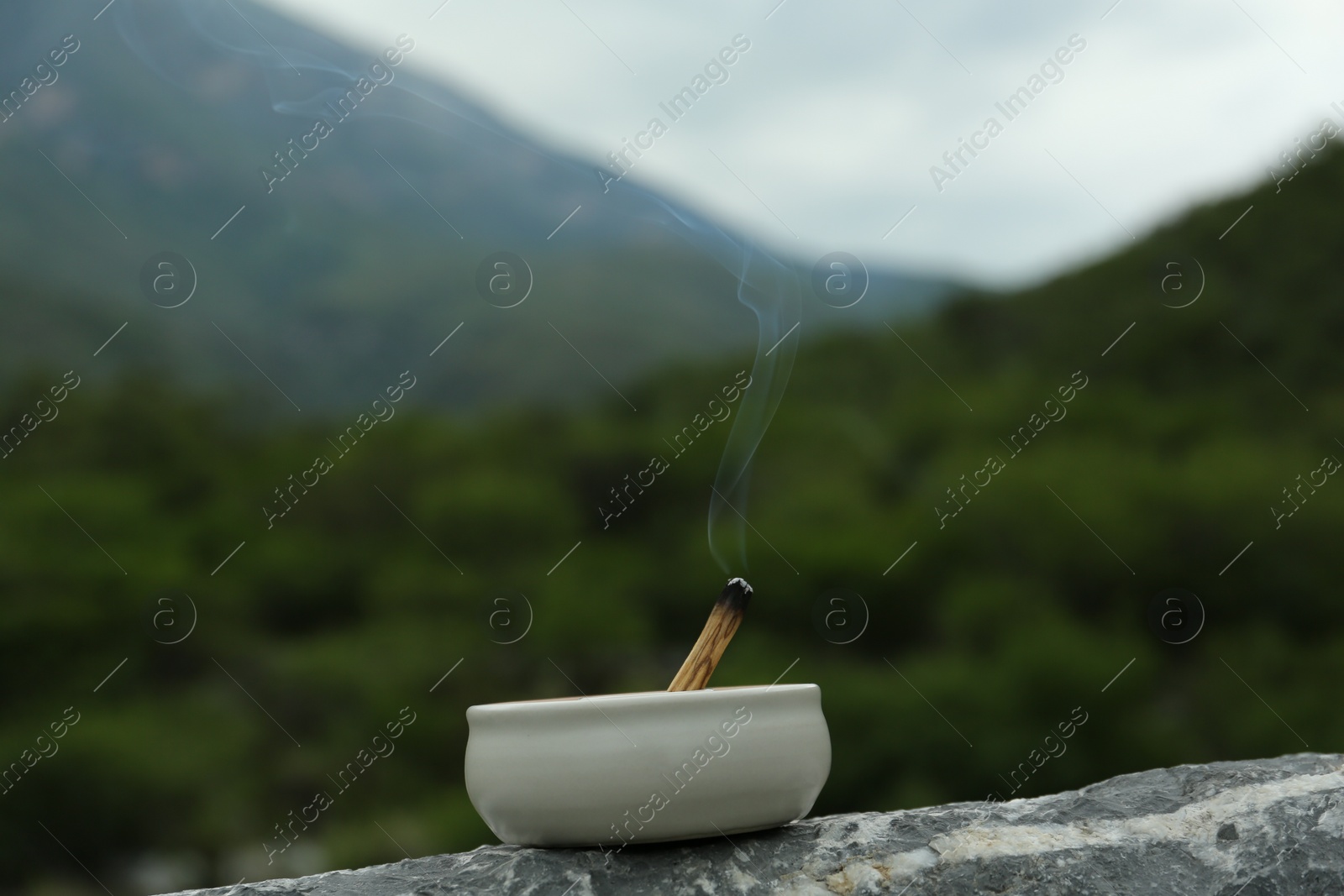 Photo of Burning palo santo stick on stone surface in high mountains