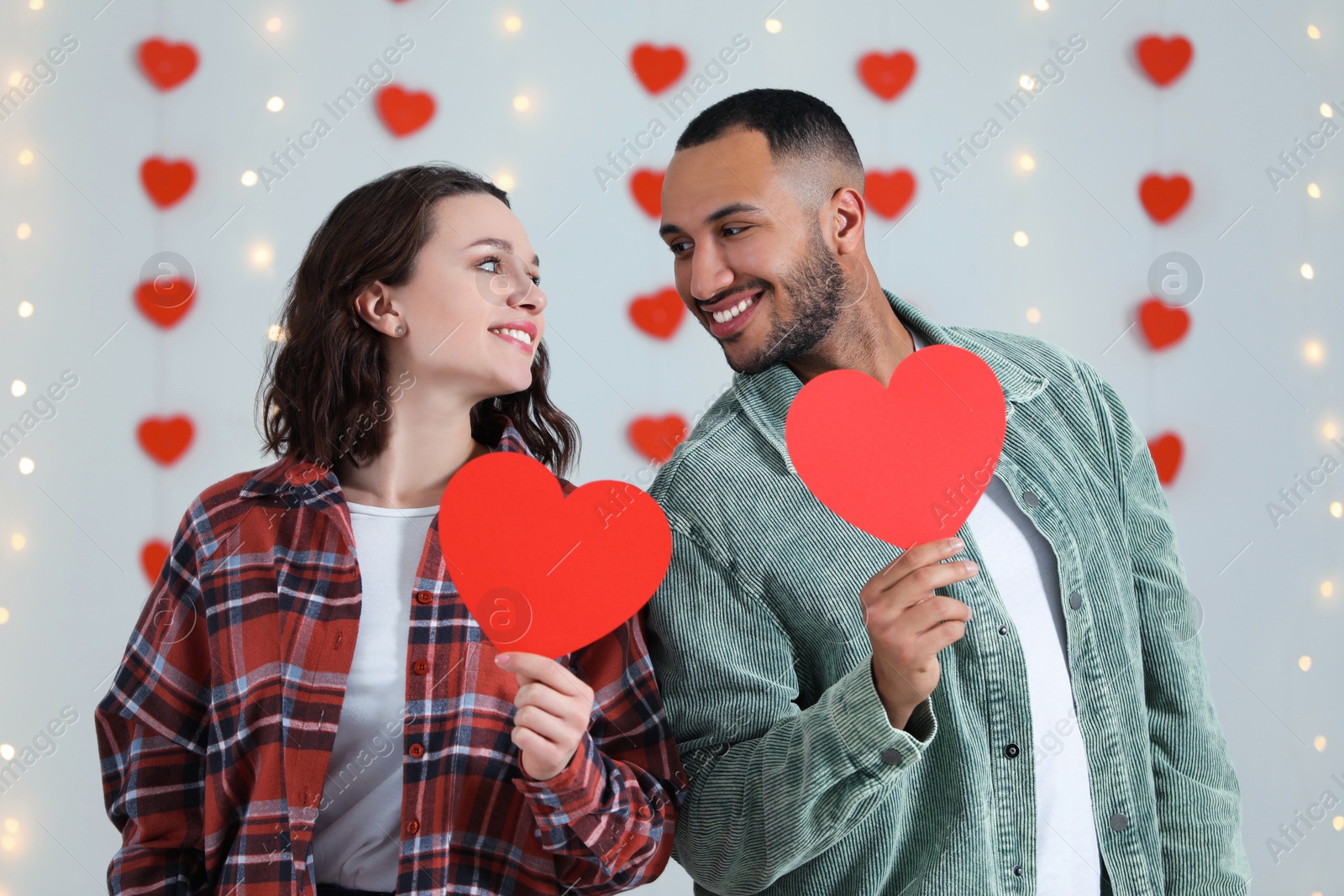 Photo of Lovely couple with red paper hearts indoors. Valentine's day celebration