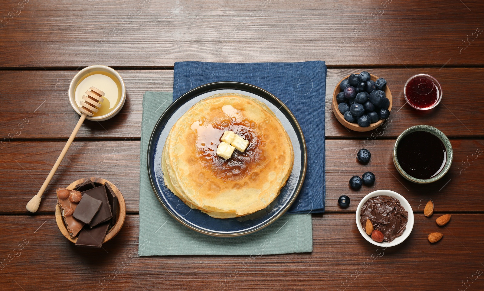 Photo of Delicious crepes with different products on wooden table, flat lay