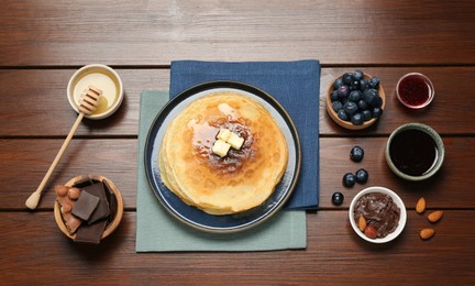 Photo of Delicious crepes with different products on wooden table, flat lay
