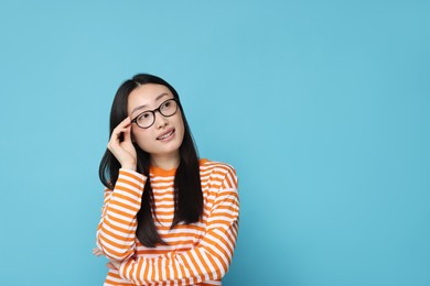 Photo of Portrait of happy woman in glasses on light blue background. Space for text