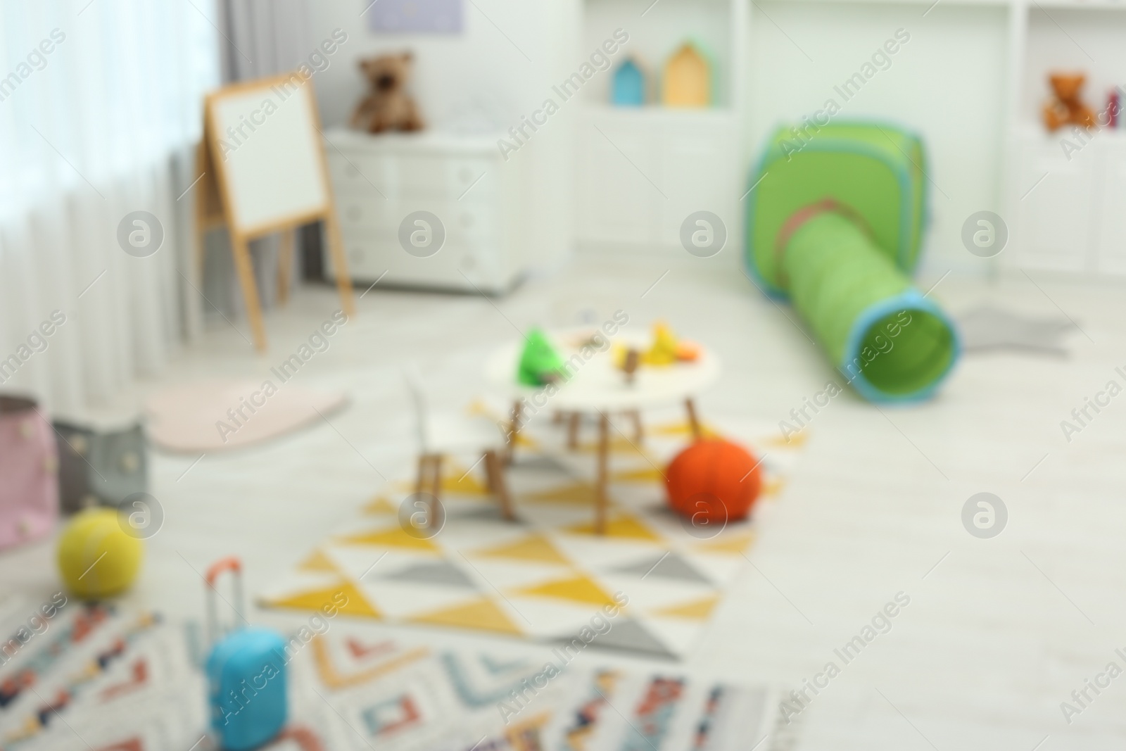 Photo of Blurred view of child`s playroom with different toys and furniture. Stylish kindergarten interior