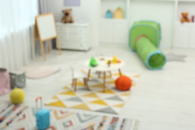 Blurred view of child`s playroom with different toys and furniture. Stylish kindergarten interior