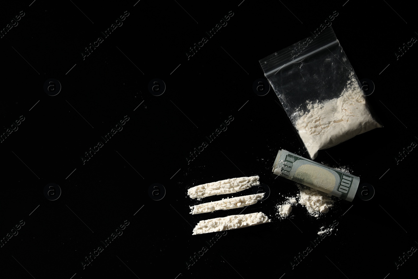 Photo of Plastic bag with hard drug and rolled dollar banknote on black background,, flat lay. Space for text