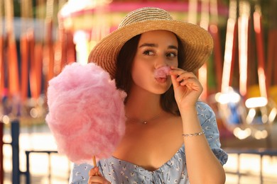 Photo of Beautiful young woman with cotton candy having fun at funfair
