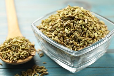 Bowl and spoon with fennel seeds on light blue wooden table, closeup