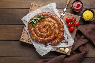 Delicious homemade sausage with spices served on wooden table, flat lay