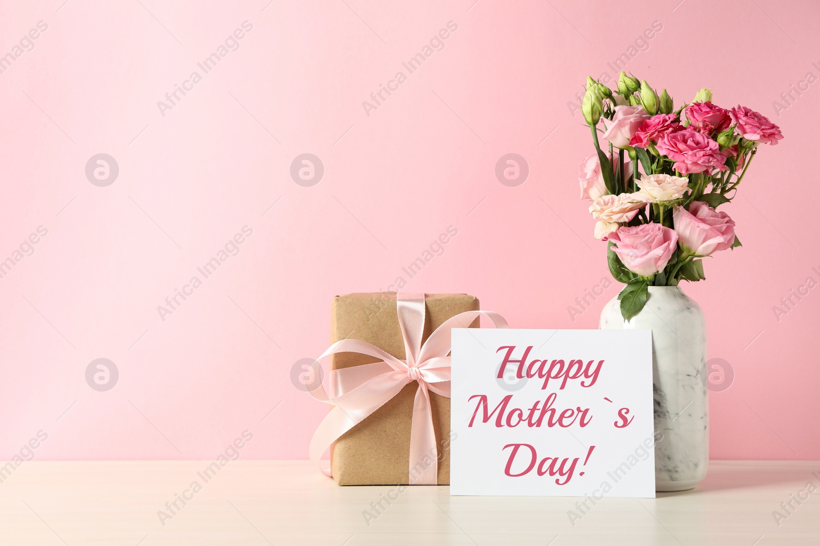 Image of Happy Mother's Day greeting card, gift box and bouquet of beautiful flowers on white wooden table