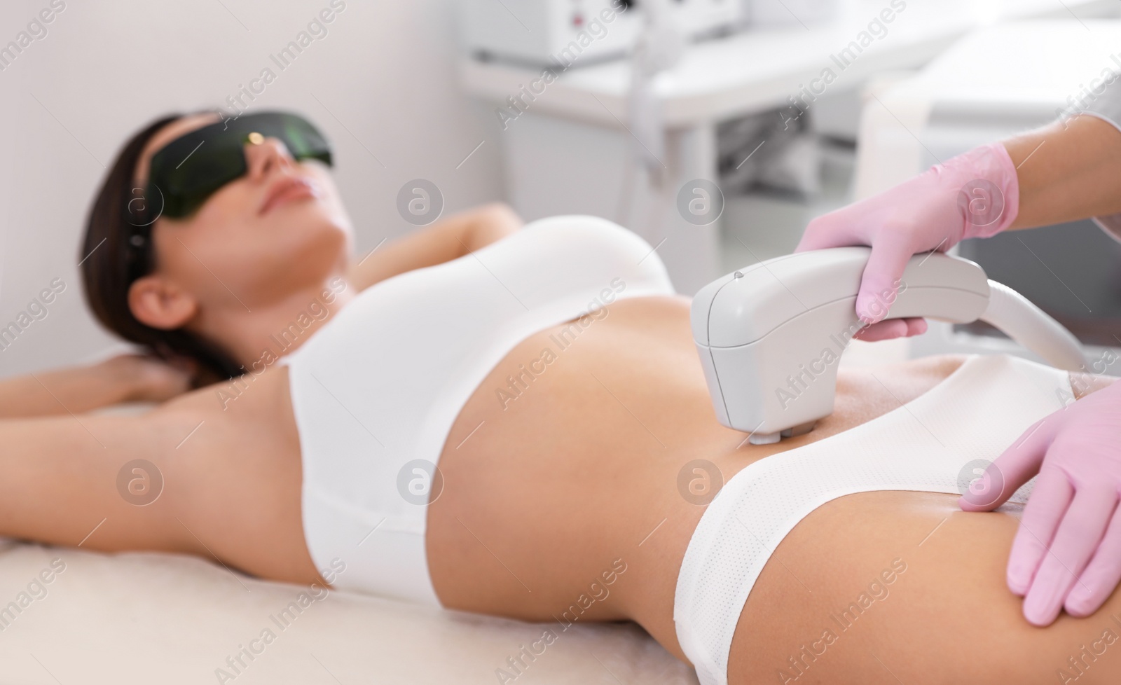 Photo of Young woman undergoing laser epilation procedure in beauty salon