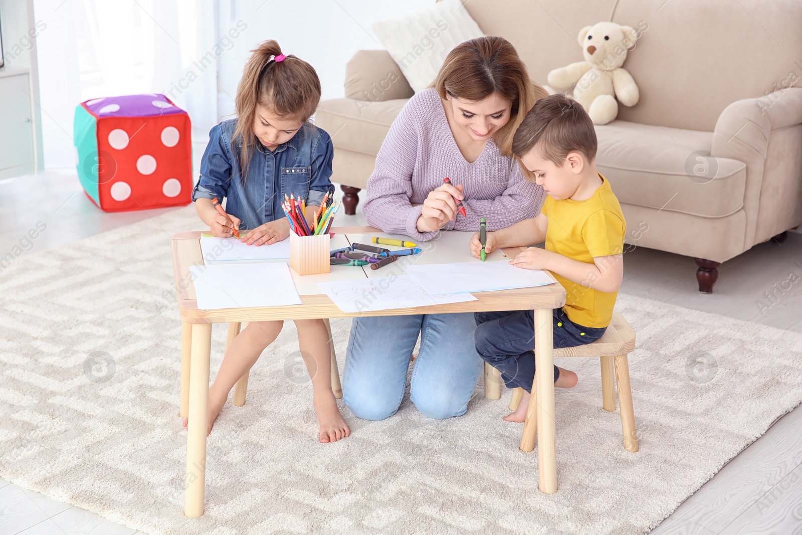 Photo of Cute little children and their nanny drawing at home