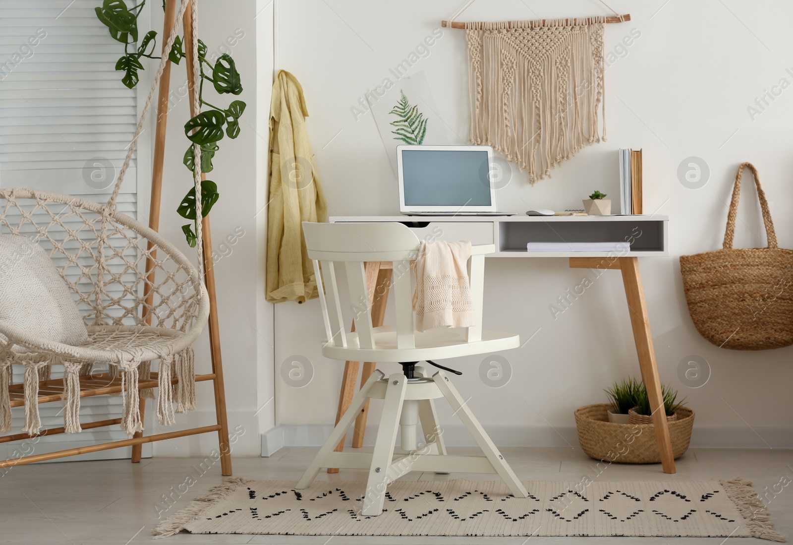 Photo of Stylish room interior with workplace and hanging chair