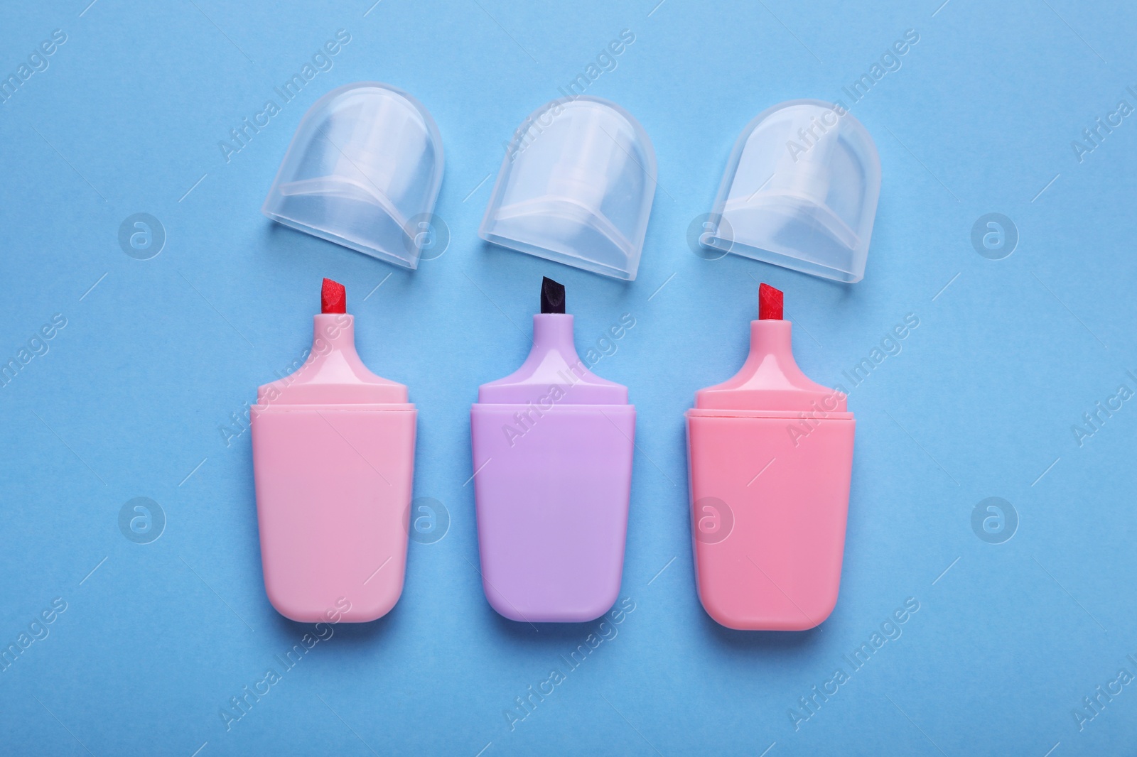Photo of Colorful markers with caps on light blue background, flat lay