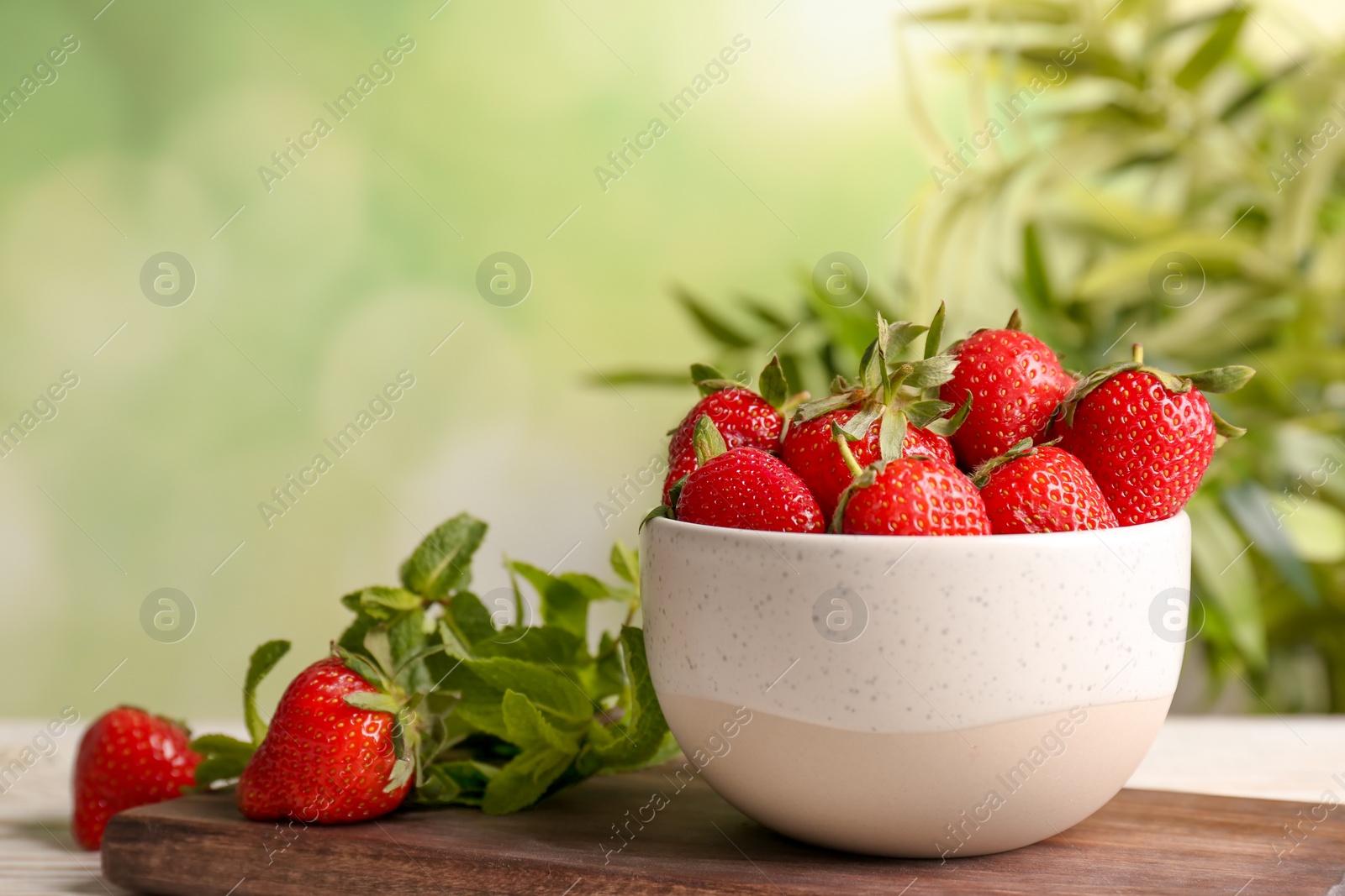 Photo of Bowl with ripe red strawberries on table