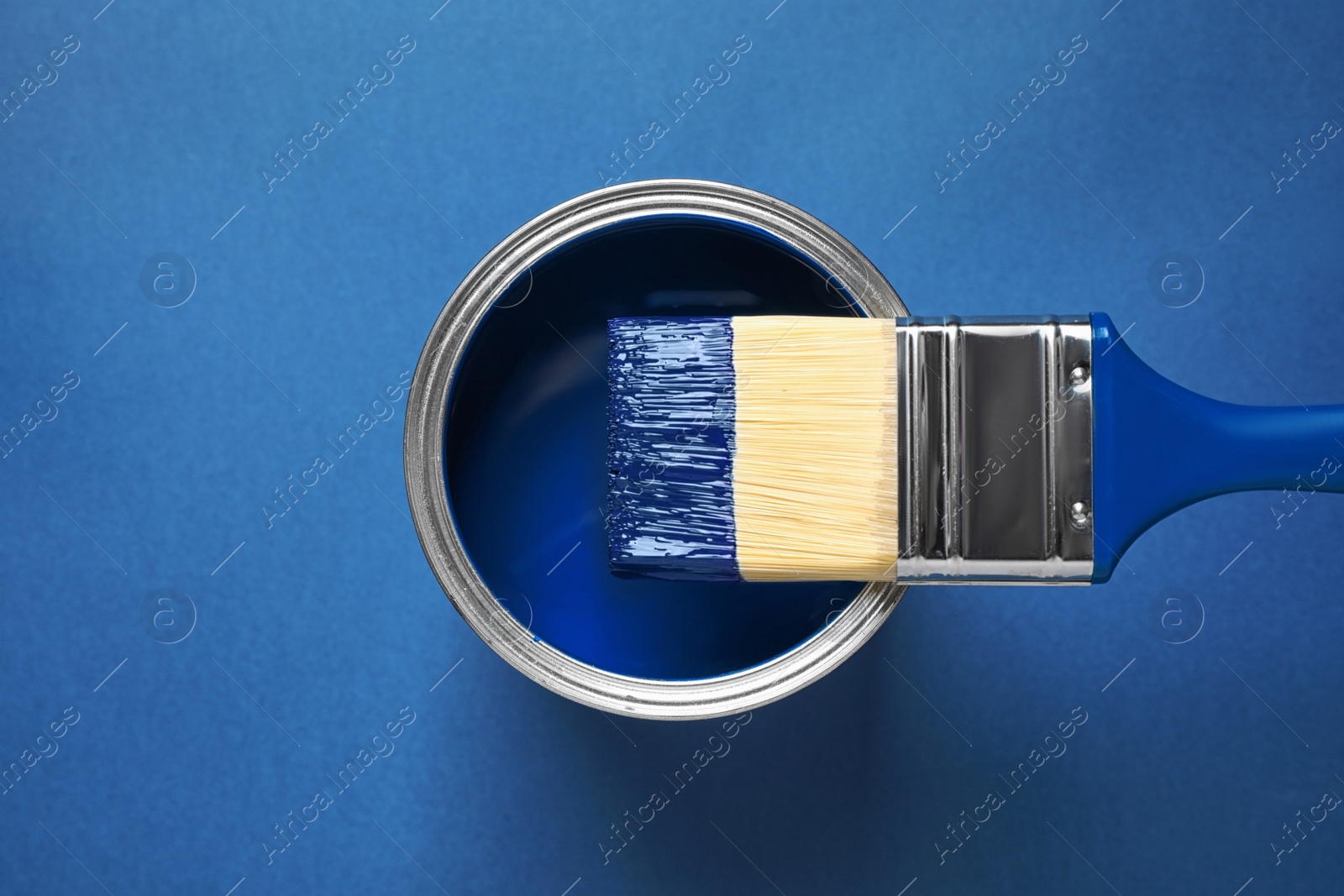 Photo of Can of paint and brush on bright background, top view. Color of the year 2020 (Classic blue)