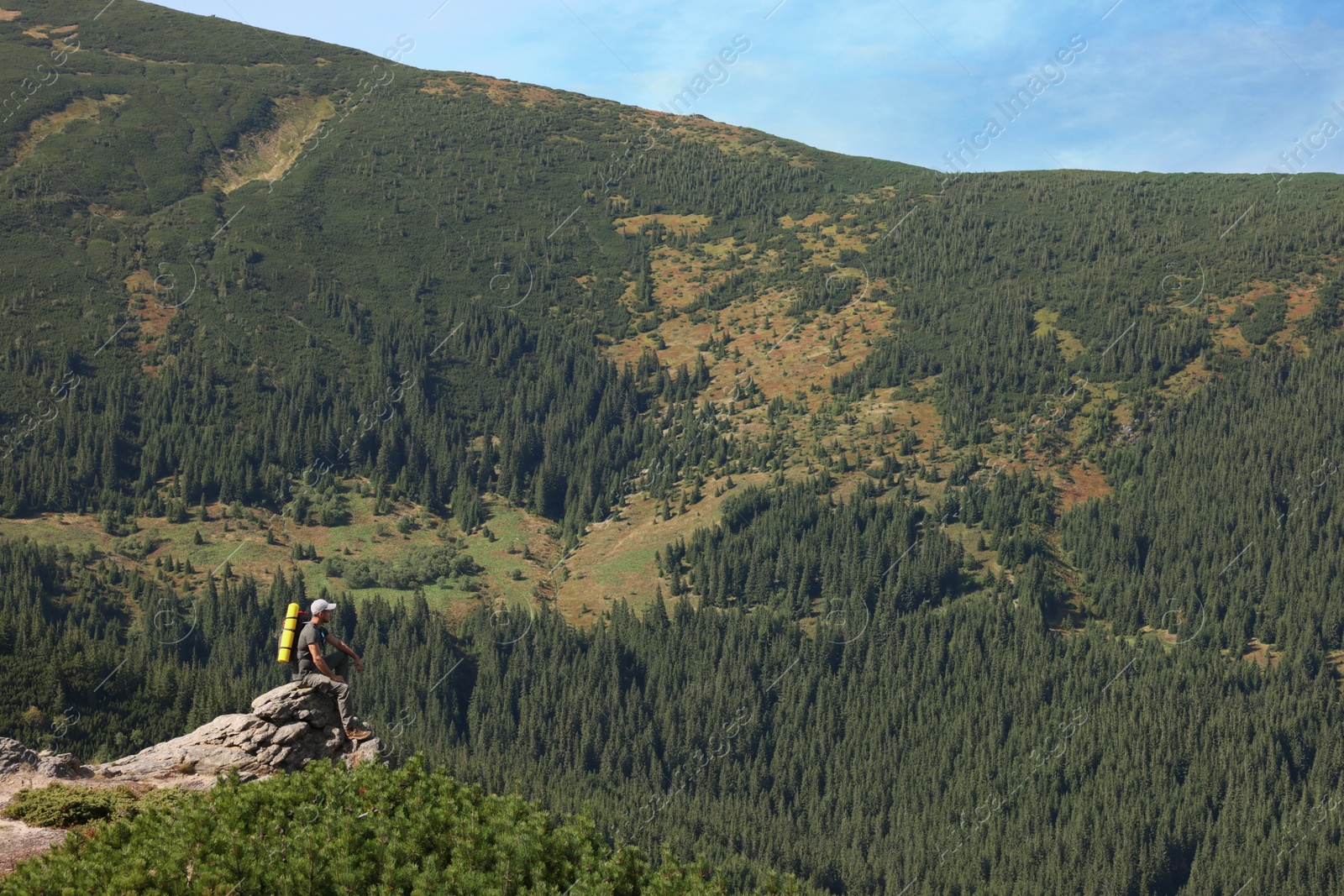 Photo of Tourist with backpack on cliff in mountains. Space for text