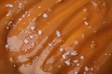 Delicious caramel sauce with sea salt as background, closeup