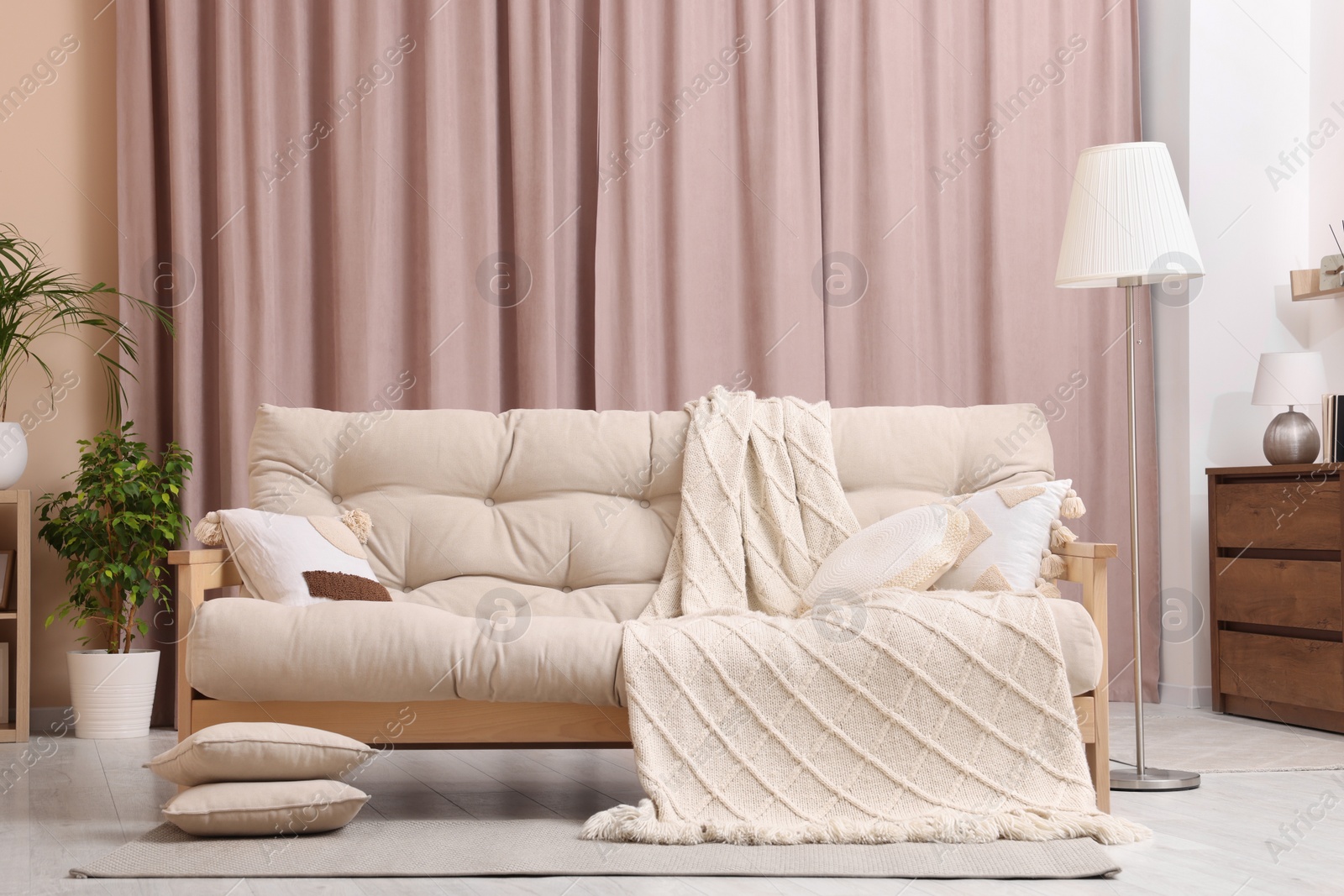 Photo of Comfortable sofa, cushions and blanket in cozy room. Interior design