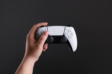 Photo of Woman using wireless game controller on dark background, closeup