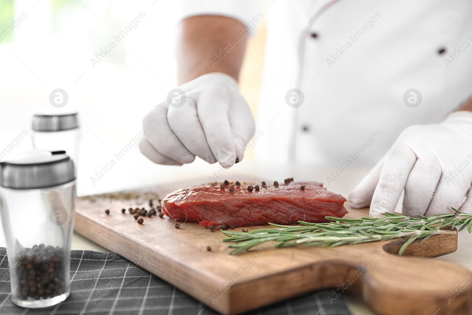 Photo of Professional chef cooking meat on table in kitchen, closeup