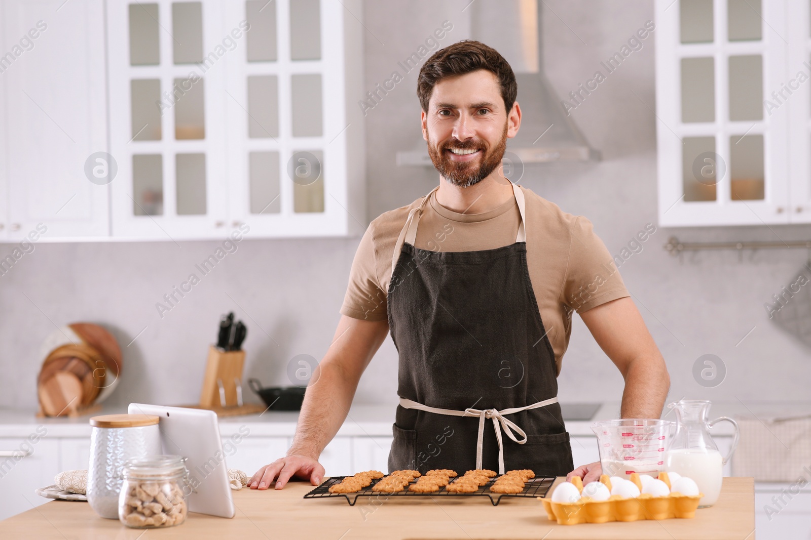 Photo of Man with freshly baked cookies at table in kitchen. Online cooking course