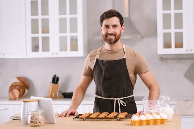 Photo of Man with freshly baked cookies at table in kitchen. Online cooking course