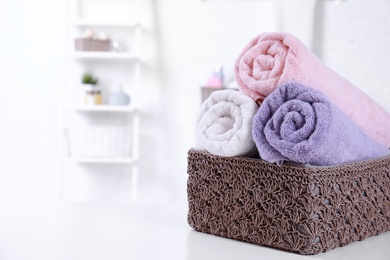 Photo of Basket with rolled fresh towels on table in bathroom. Space for text