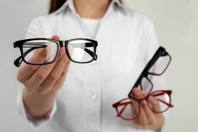 Woman with different glasses on light background, closeup