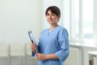 Photo of Portrait of smiling medical assistant with clipboard and pen in hospital