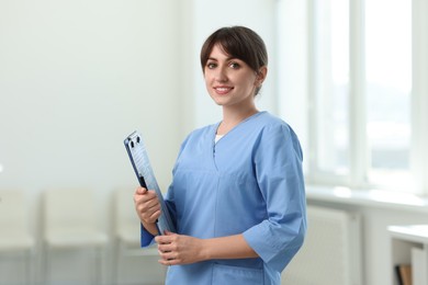 Portrait of smiling medical assistant with clipboard and pen in hospital