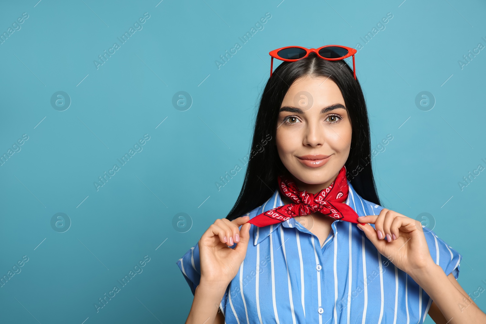 Photo of Fashionable young woman in stylish outfit with bandana on light blue background, space for text