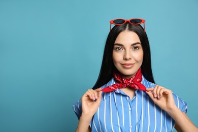 Fashionable young woman in stylish outfit with bandana on light blue background, space for text