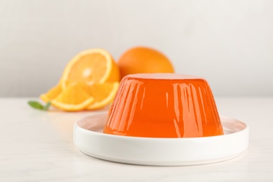 Photo of Plate with tasty jelly and oranges on white table, space for text