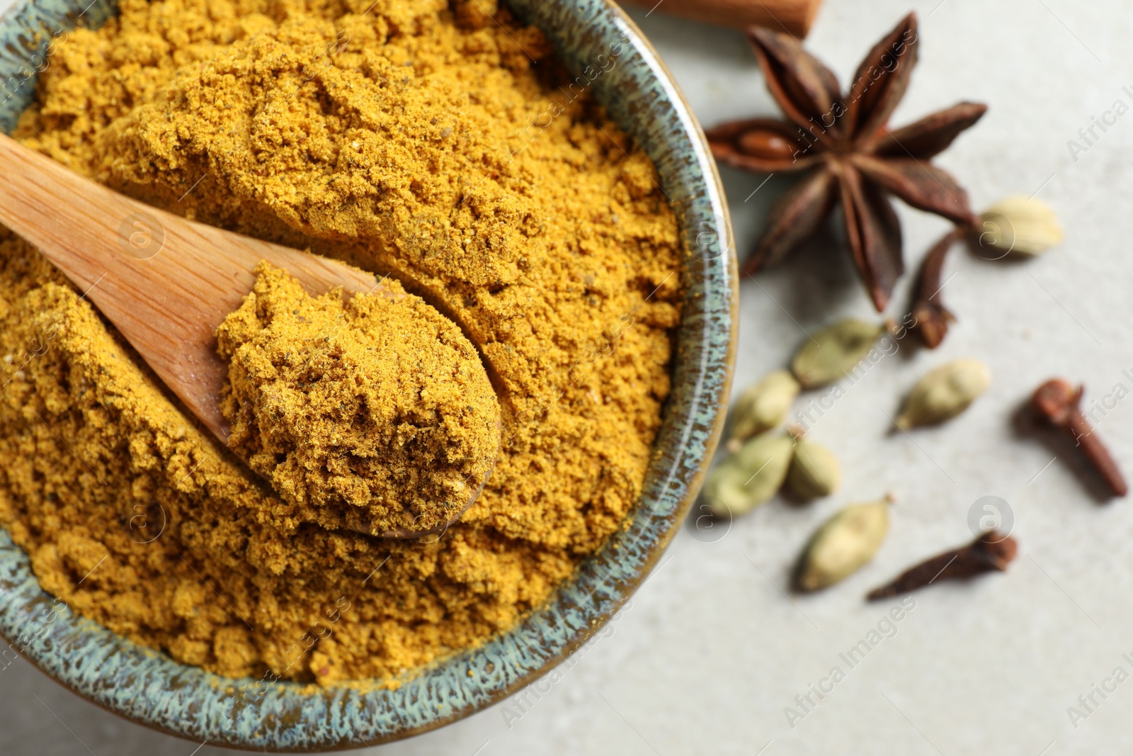 Photo of Dry curry powder in bowl and other condiments on light table, flat lay