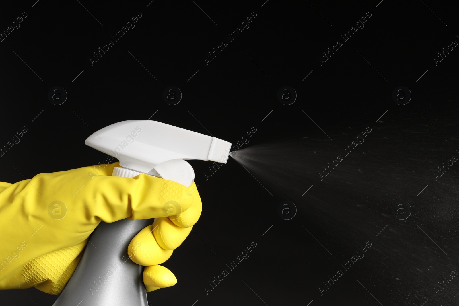 Photo of Woman spraying liquid from bottle on black background, closeup. Space for text