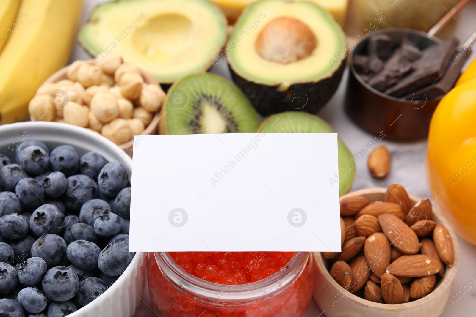 Photo of Many different products with blank card on white table, closeup and space for text. Natural sources of serotonin