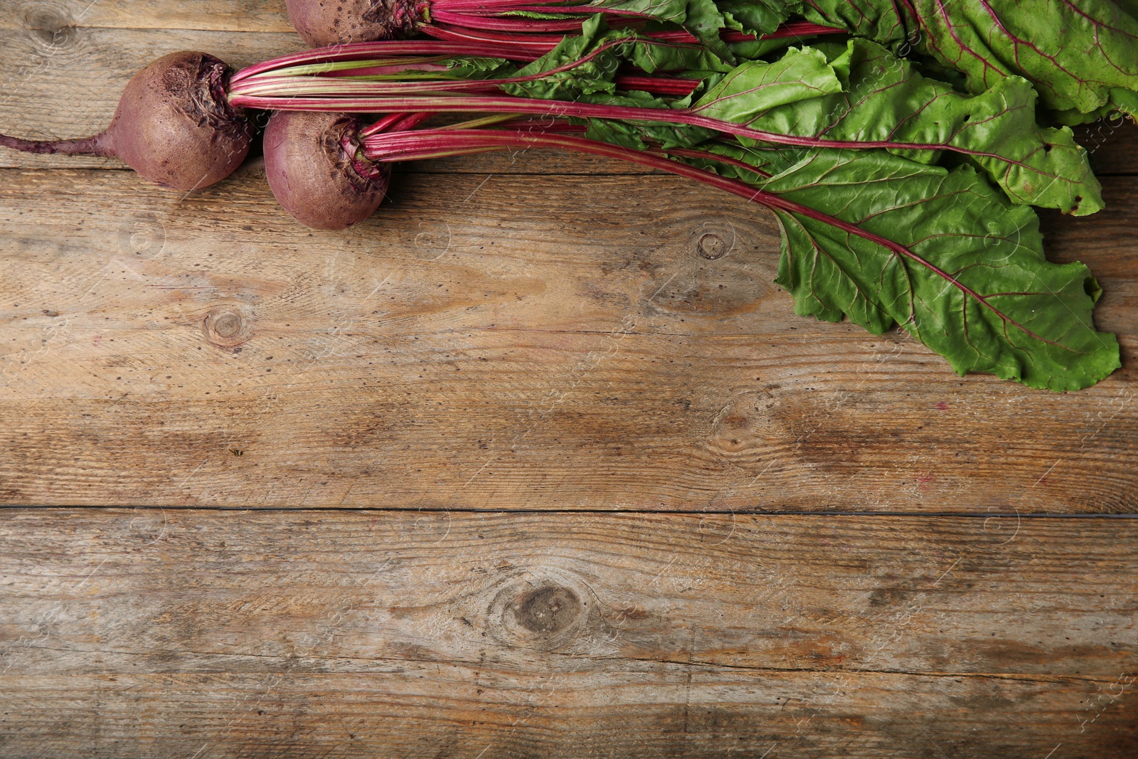 Photo of Fresh beets with leaves on wooden table, flat lay. Space for text