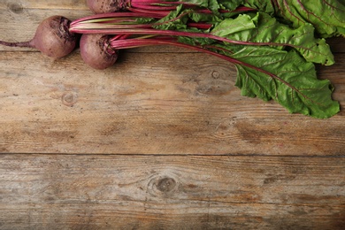 Photo of Fresh beets with leaves on wooden table, flat lay. Space for text